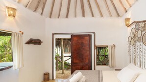 A room with a bed, a wooden door, a woven wall hanging, and a view of greenery outside. - Yaxchen Tulum Cabañas & Cenote (Tulum)