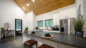 Een moderne keuken met witte kasten, een roestvrijstalen koelkast en een centraal eiland met barkrukken.