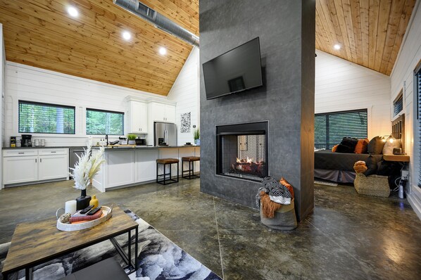 A modern kitchen with white cabinets, a large window, and a built-in stove.