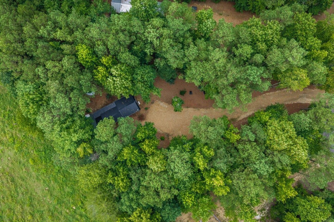 Una vista aerea di una zona boschiva con un piccolo edificio e un'area disboscata.