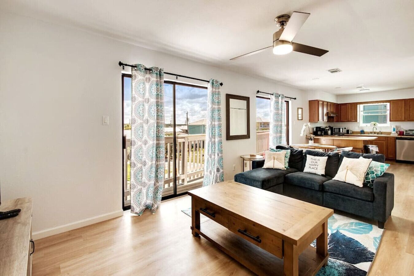 Ein modernes Wohnzimmer mit Sofa, Couchtisch und Blick auf einen Balkon mit gemusterten Vorhängen.