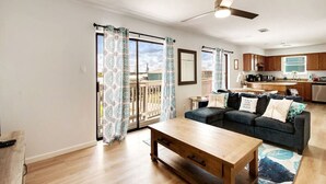 Un salon moderne avec un canapé, une table basse et une vue sur un balcon agrémenté de rideaux à motifs.