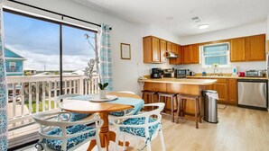 Une cuisine moderne avec des meubles en bois, un îlot central et un coin repas avec des chaises bleues et blanches.