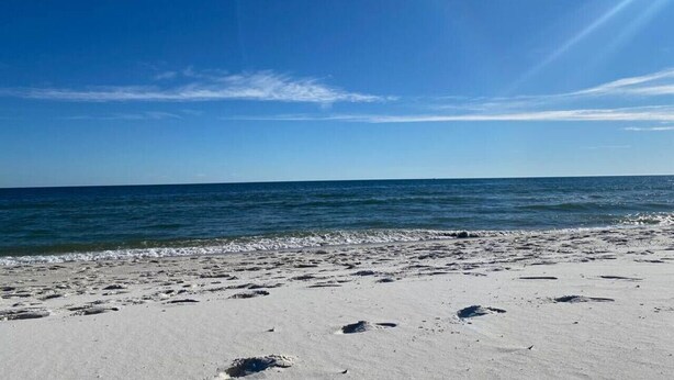 Une plage avec un ciel dégagé et une mer calme.