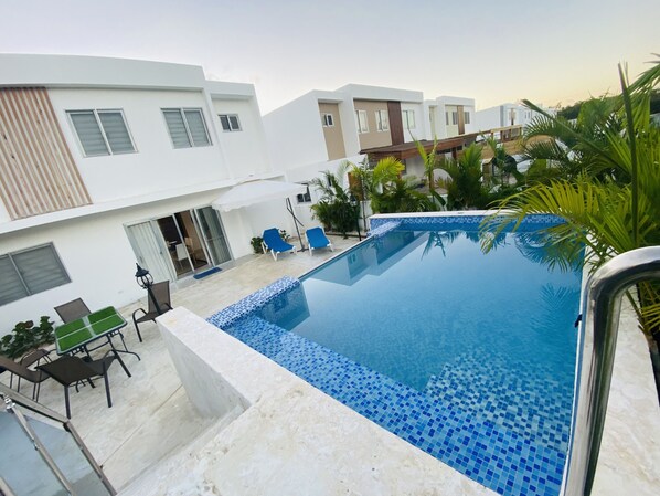 Relax by the pool surrounded by a deck with lounge chairs and a table.