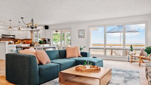 Ein geräumiges Wohnzimmer mit einer Eckcouch, einem Holztisch und Blick auf den Balkon.