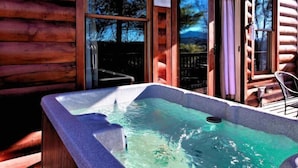 Eine Holzhütte mit Whirlpool auf der Veranda.