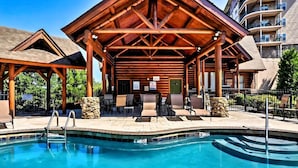Ein Poolbereich mit einer Holzpergola, Liegestühlen und einer Steinmauer.