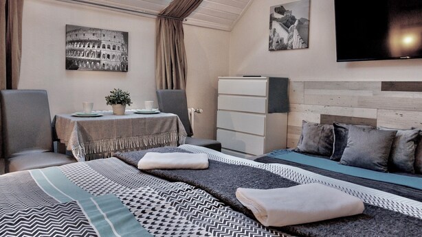 A hotel room with a bed, a desk with a plant, a TV, and artwork on the walls. - Nestled in the Quiet Hills of Prague, Attic Suite 2 (Hlavní mesto Praha)