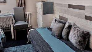 A bedroom with a bed, a TV, a chair, a table, and a window with curtains. - Nestled in the Quiet Hills of Prague, Attic Suite 2 (Hlavní mesto Praha)