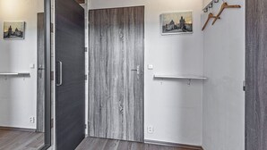 A hallway with a wooden floor, a door with a metal handle, and a wall-mounted light fixture. - Nestled in the Quiet Hills of Prague, Attic Suite 2 (Hlavní mesto Praha)