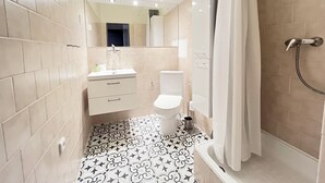 A modern bathroom with beige tiles, a white sink, a toilet, and a shower with a curtain. - Nestled in the Quiet Hills of Prague, Attic Suite 2 (Hlavní mesto Praha)