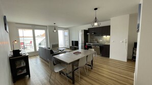 A modern apartment with a dining area, kitchen, and a balcony with a view. - New appartment near the center for 6 people with car park (LACANAU OCEAN)