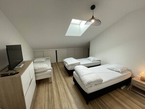 Pieni huone, jossa on kaksi sänkyä, televisio ja kattovalokuvio.