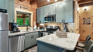 A modern kitchen with grey cabinets, stainless steel appliances, and a granite countertop. - Rustic 2BR Log Cabin w/ Private Indoor Pool & Hot Tub — Near Pigeon Forge (Sevierville)