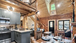 Eine geräumige Küche mit modernen Geräten, ein Essbereich mit einem Holztisch, der für eine Mahlzeit gedeckt ist, und eine gemütliche Wohnarea mit Kamin.
