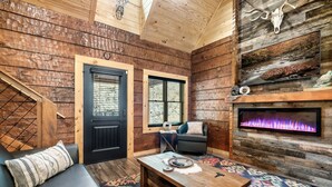 Ein gemütliches Blockhaus-Interieur mit Kamin, einer Couch und einem Couchtisch.