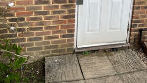 A white door with a glass panel, a brick wall, a metal box with a keypad, and a wall-mounted light fixture. - Captivating Apartment Near Gatwick (Crawley)