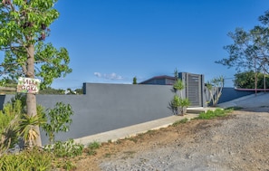 En lukket ejendom med et skilt, der viser "Villa GGKI", og en moderne bygning i baggrunden.