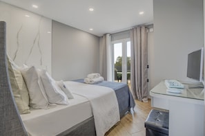 Et moderne hotelværelse med seng, skrivebord med computer og udsigt til det fri.