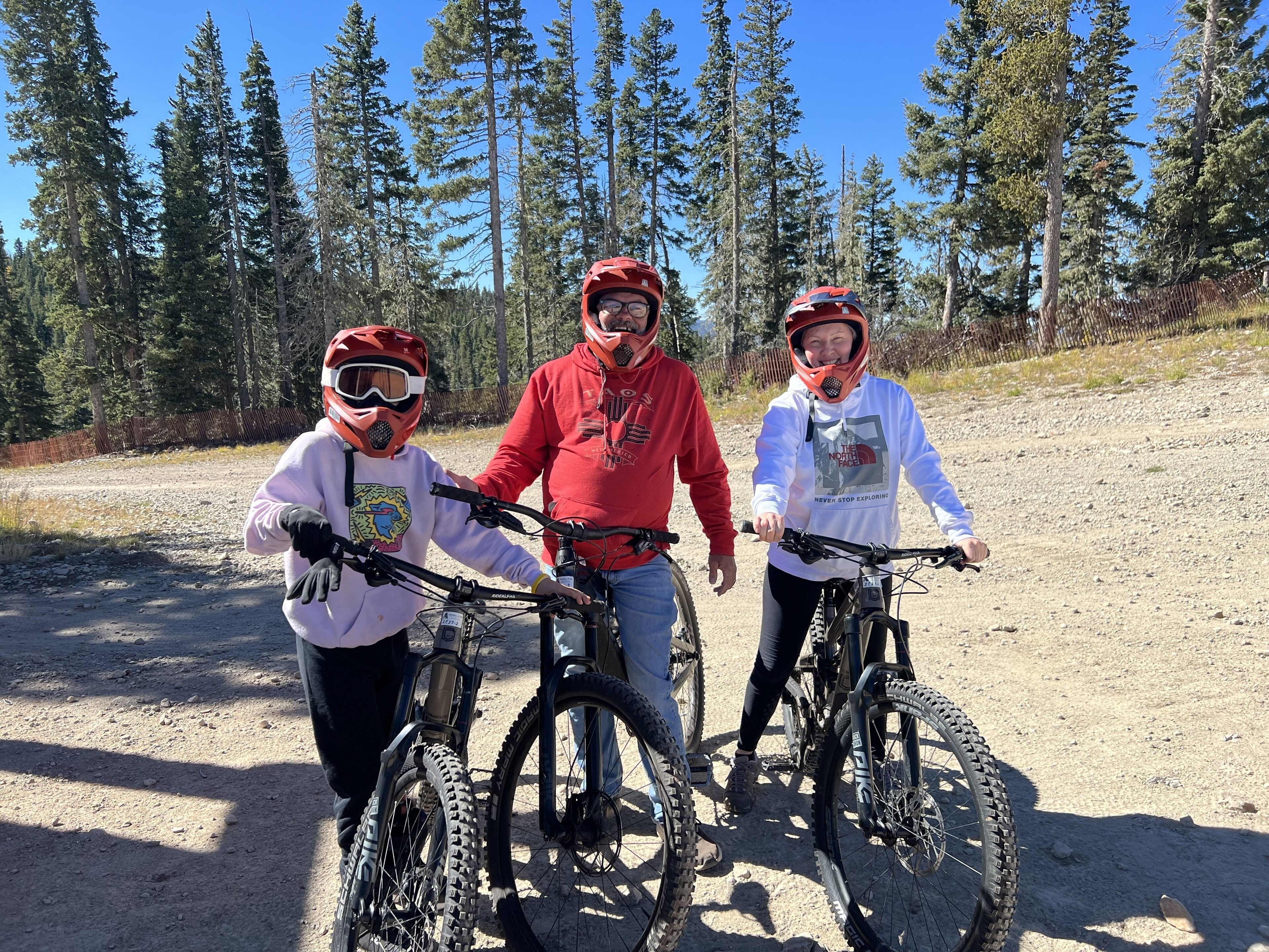 Three people on bicycles in a forested area.