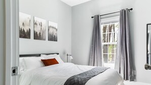 Un dormitorio con una cama, una ventana con cortinas y tres cuadros colgados en la pared.