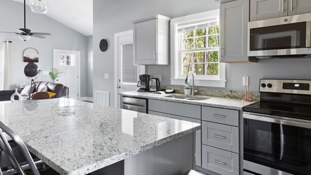 Una cocina moderna con encimeras de granito, electrodomésticos de acero inoxidable y un amplio ventanal.