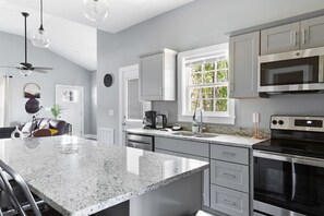 Una cocina moderna con encimeras de granito, electrodomésticos de acero inoxidable y un amplio ventanal.