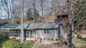 A two-story house with a porch, a covered front porch area, and a small deck. - Still Standing! Cozy Cottage, Incredible Location! (Lake Lure)