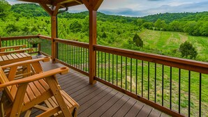 A wooden deck with outdoor seating and a view of a lush green landscape. - Gorgeous custom log cabin on 185 acres (Dellrose)