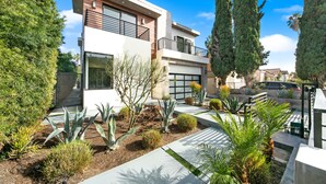 A modern two-story house with a balcony, surrounded by a landscaped garden with various plants and trees. - Beverly Hills Playhouse with Rooftop & Pool (Los Angeles)