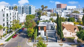 Un quartier résidentiel urbain moderne, caractérisé par des immeubles à plusieurs étages, une diversité de styles architecturaux et une rue bordée de voitures garées et d’arbres.