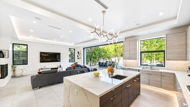 A modern kitchen with a marble island, dark cabinetry, and a large window providing a view of the outdoors. - Beverly Hills Playhouse with Rooftop & Pool (Los Angeles)