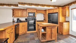 Eine Küche mit Holzausstattung, einer Mikrowelle, einem Backofen und einem Kühlschrank.