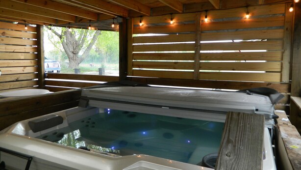 Una cabaña de madera con jacuzzi, paredes de madera y una ventana con vista a un árbol.