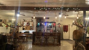 Un interior rústico con una zona de bar, muebles de madera y adornos de asta.