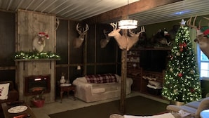 Un interior rústico con chimenea, un árbol de Navidad y cornamentas de ciervo montadas en la pared.