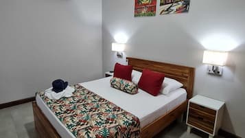 A hotel room with a bed, two wall-mounted lamps, a nightstand, and two wall art pieces.