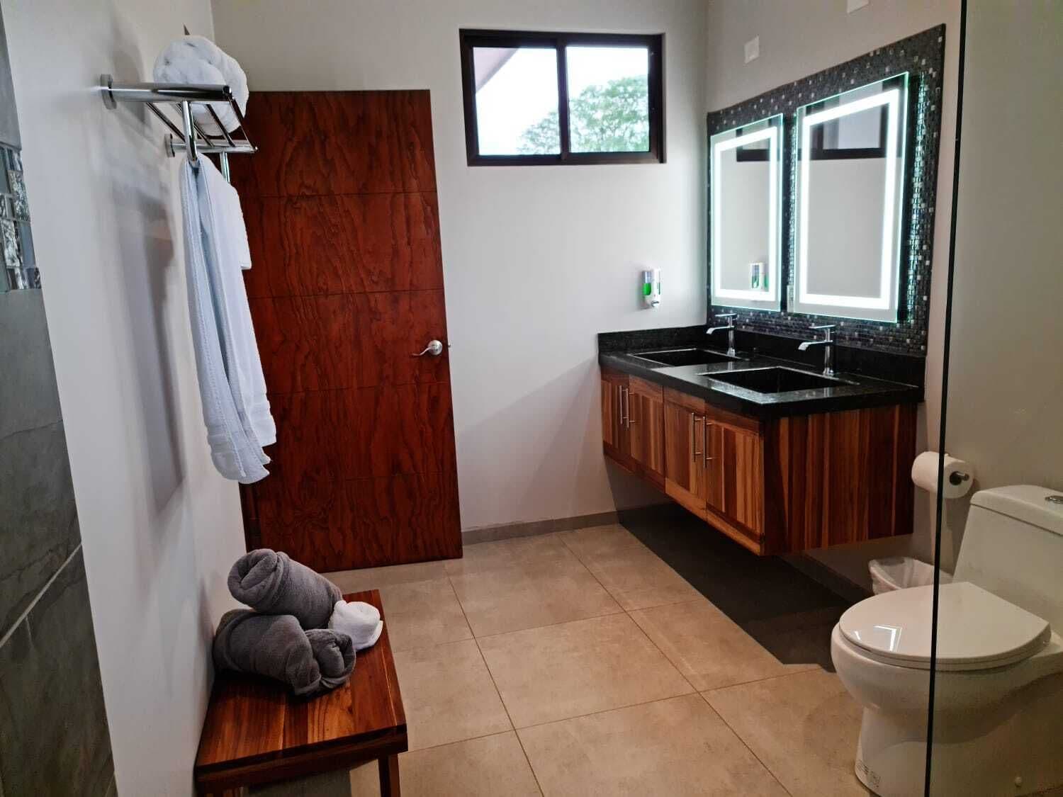 A bathroom with a wooden vanity, a sink, a toilet, and a mirror.