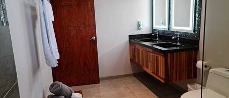 A bathroom with a wooden vanity, a sink, a toilet, and a mirror.