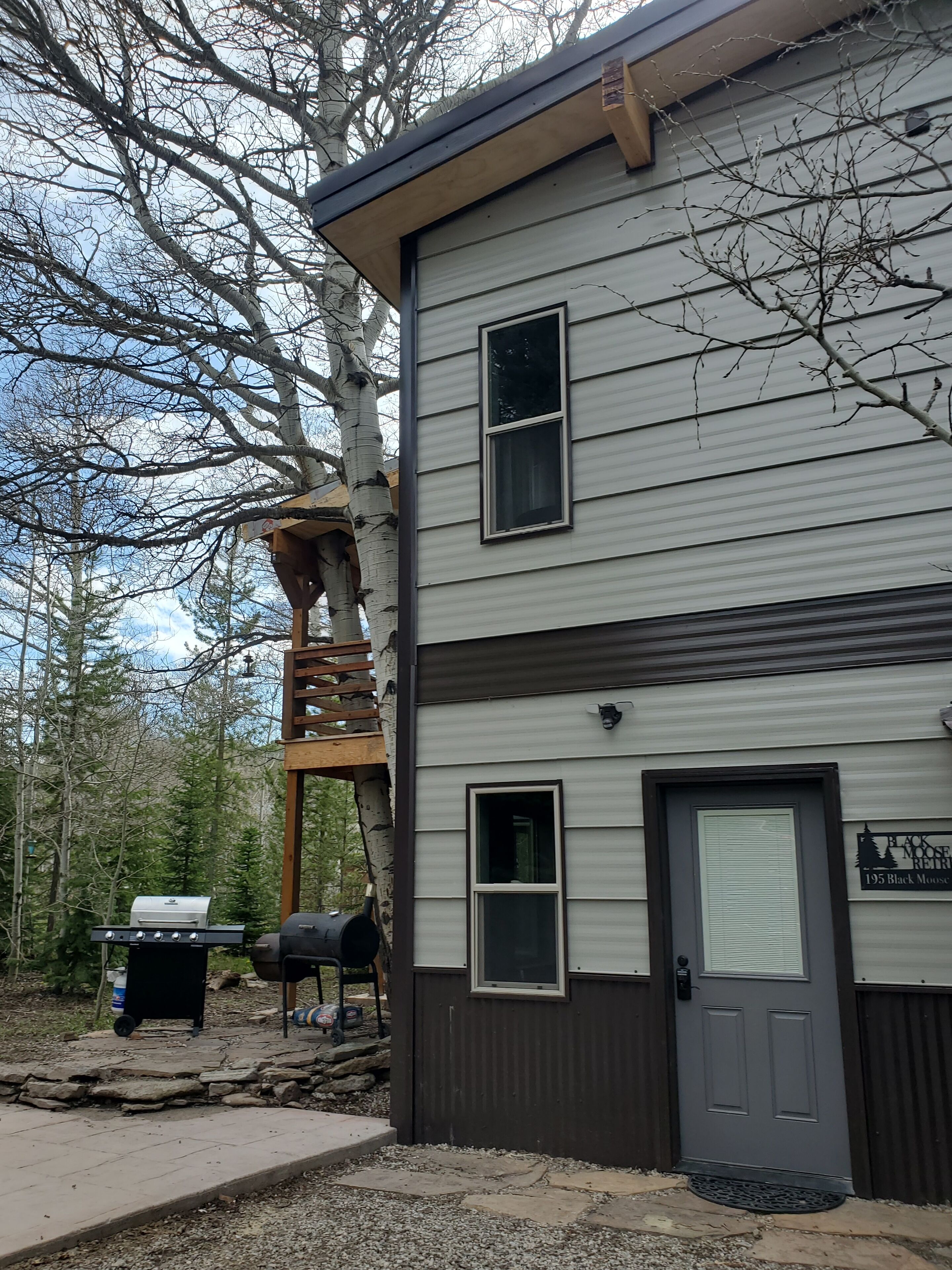 A two-story building with a front door, a small porch, and a grill area.