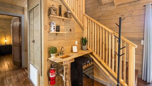 A wooden interior with a staircase, a sink, and a fire extinguisher.