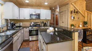 A modern kitchen with stainless steel appliances, white cabinets, and a granite countertop.