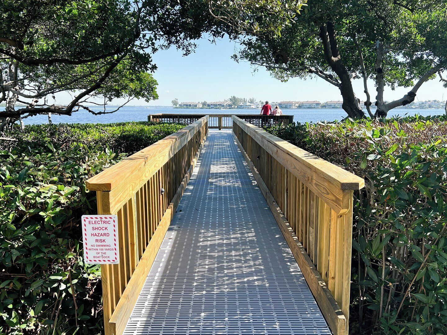 Une promenade en bois mène à un quai où un panneau d’avertissement signale le risque d’électrocution.