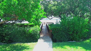 A pathway leading to a wooden structure surrounded by lush green trees and grass. - Runaway Bay 107 - Beach, Pool, gym and much more (Unknown)
