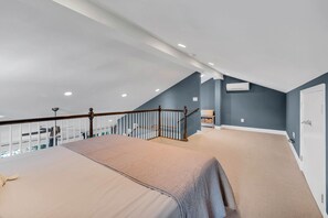 Ein geräumiger Raum mit hoher Decke, einer Holztreppe und einem großen Bett.