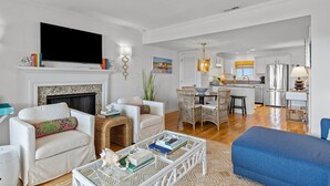 Una sala moderna con chimenea, televisor y comedor con muebles de mimbre.