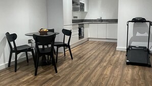 A modern kitchen with white cabinets, a microwave, and a dishwasher. There is a dining area with a table and chairs. - Luxury 2-bed Apartment in Manchester With Parking (Salford)