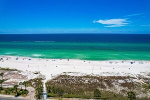 A beach with clear turquoise water, white sand, and a few umbrellas.