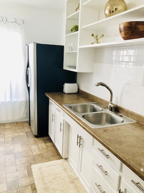 Enjoy cooking in this kitchen with a stainless steel sink, toaster, and white cabinetry.